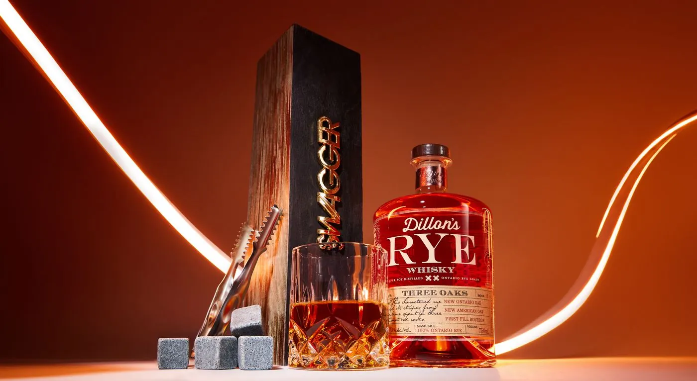 Editorial real photograph of a whisky bottle, glass and wooden presentation objects under amber light